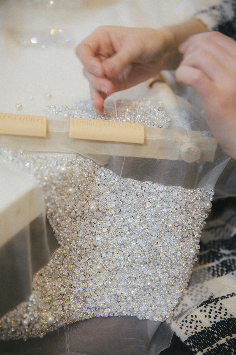 A Phillipa Lepley seamstress hand applying crystals to a bespoke gown.